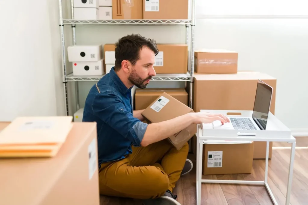 Cómo desarrollar un eCommerce exitoso 6 blog uhura como desarrollar hombre hispano sentado en el piso de su oficina mientras escribe en su laptop y chequea ordenes de cliente de ecommerce