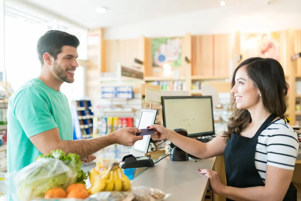hombre sonriente pagando su compra en tienda física
